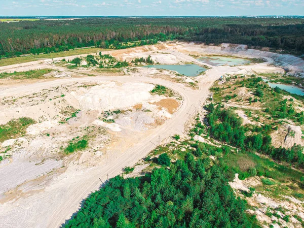 Drone view on a flooded kaolin quarry with turquoise water and white shore. Aerial survey of a kaolin pit flooded with water.