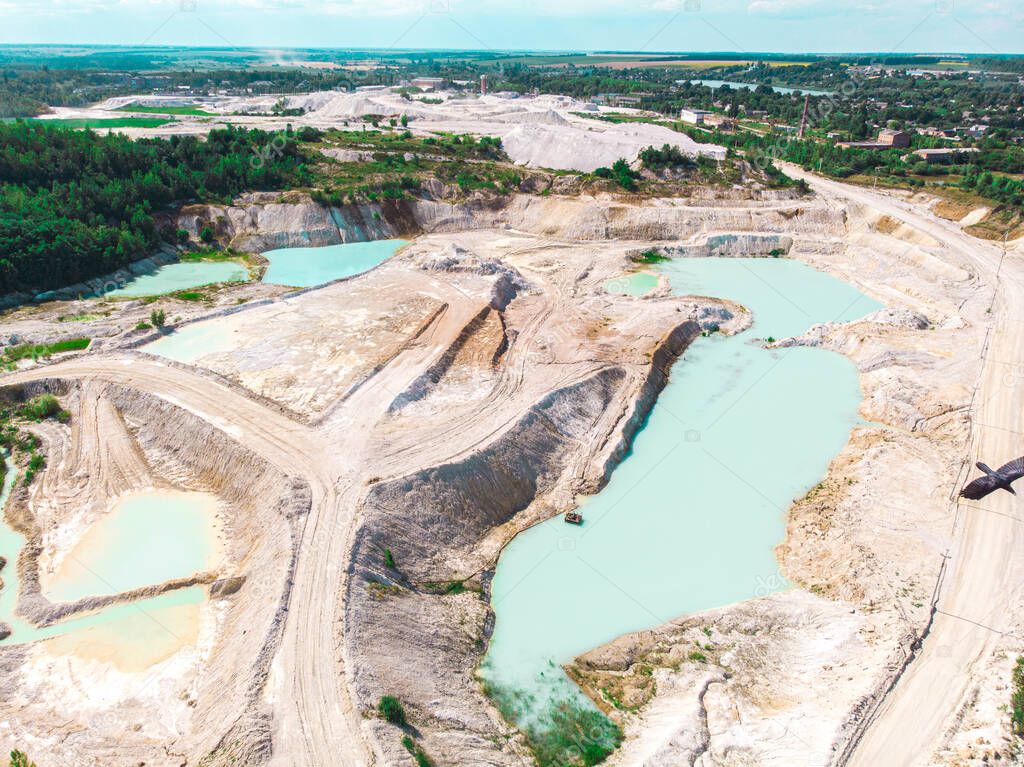 Drone view on a flooded kaolin quarry with turquoise water and white shore. Aerial survey of a kaolin pit flooded with water.