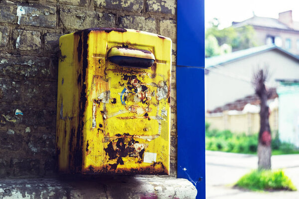 Old rusty peeling postal box on the wall. Yellow rarity postal box. Toned style photo.