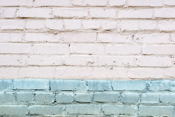 White brick wall background. Brick wall texture for design. Blue paint stripe on the down part of the wall.
