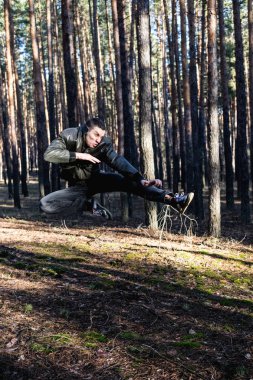 Genç bir adam bir siyah deri ceketli bir sonbahar ormanında poz suç görünüm