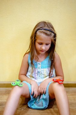 Küçük kız evde stres rahatlatmak için yeşil ve kırmızı topluca spinners ile oynamak