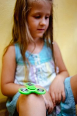 Küçük kız evde stres rahatlatmak için yeşil topluca spinner oyuncakla oynamak