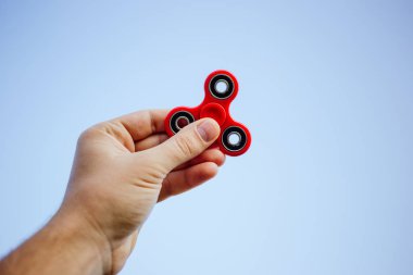 Kırmızı topluca spinner tutan bir erkek eli yakın çekim.