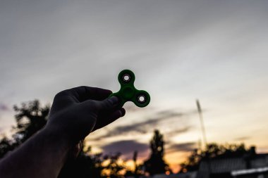 Yeşil topluca spinner tutan bir erkek eli yakın çekim.