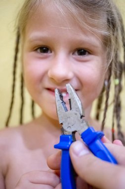 Tek bir diş ve babasının el kerpetenle olmadan küçük bir kız. Diş evde diş hekimi yardımı olmadan tek başına yapmaya çalışıyorsunuz.