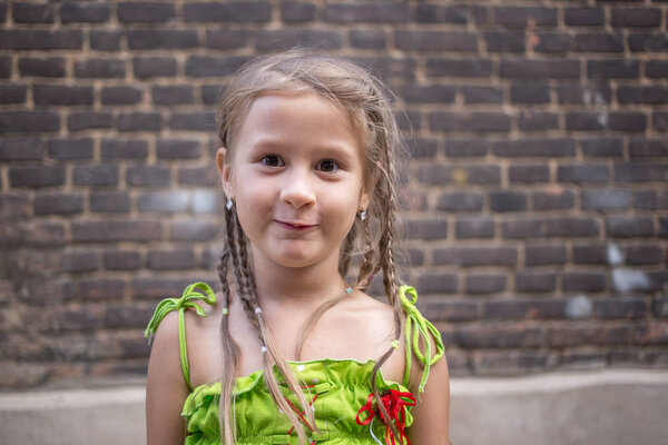 Portrait of a little girl near a brick wall.