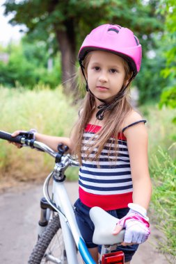 Yaz aylarında bir bisiklet yakınındaki pembe bir kask içinde küçük şirin kız