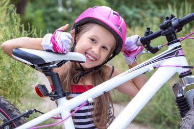 Yaz aylarında bir bisiklet yakınındaki pembe bir kask içinde küçük şirin kız