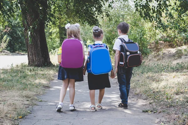 Tre Grundskoleelever Med Ryggsäckar Vandring Längs Trottoaren — Stockfoto