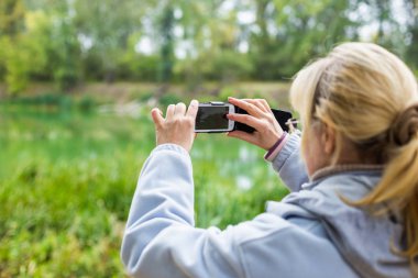 Güzel bir manzara fotoğrafını bir telefonu kullanarak sarışın bir kadın lazım.