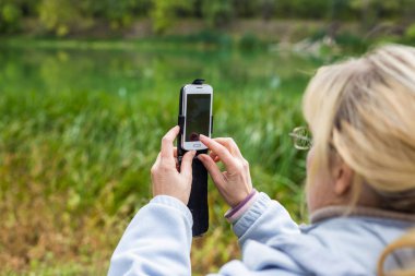 Güzel bir manzara fotoğrafını bir telefonu kullanarak sarışın bir kadın lazım.