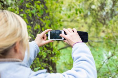 Güzel bir manzara fotoğrafını bir telefonu kullanarak sarışın bir kadın lazım.