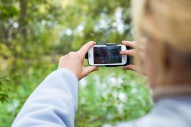 Güzel bir manzara fotoğrafını bir telefonu kullanarak sarışın bir kadın lazım.