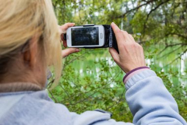 Güzel bir manzara fotoğrafını bir telefonu kullanarak sarışın bir kadın lazım.