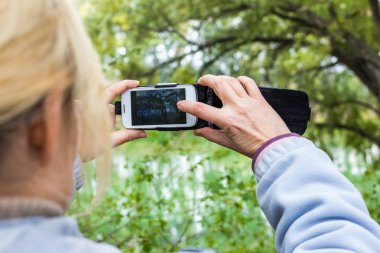 Güzel bir manzara fotoğrafını bir telefonu kullanarak sarışın bir kadın lazım.
