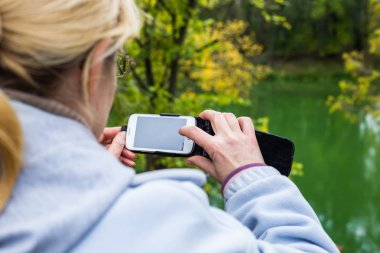 Güzel bir manzara fotoğrafını bir telefonu kullanarak sarışın bir kadın lazım.