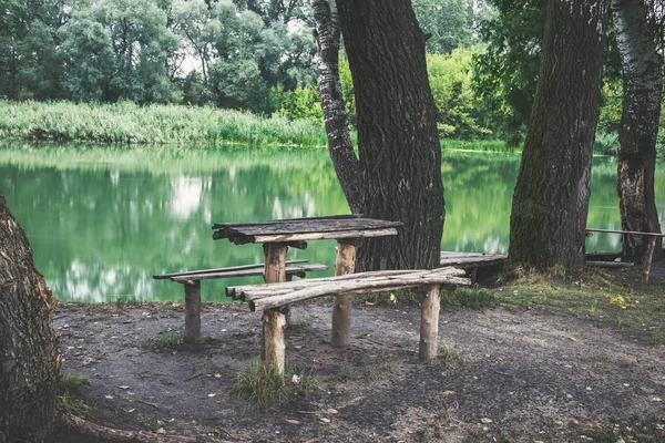 A wooden table and a bench on the river bank. A beautiful place to relax