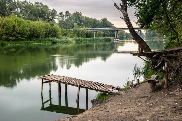 stock image Pier on a calm river in the summer. Wooden pier bridge in the morning. Place for fishing in the river. Toned, style photo