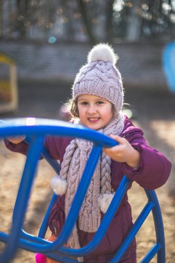 Sonbaharda bir oyun alanı üzerinde sevimli küçük bir kız