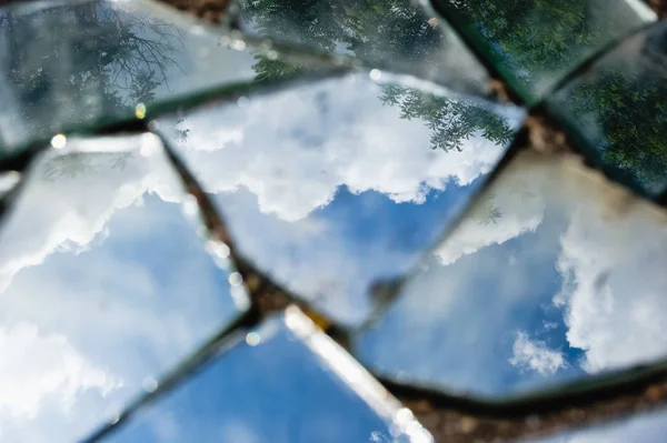 Bir ayna kirli kırık parçalar halinde kabarık bulutlar mavi bir gökyüzü yansımasıdır. Renkli şık fotoğraf.