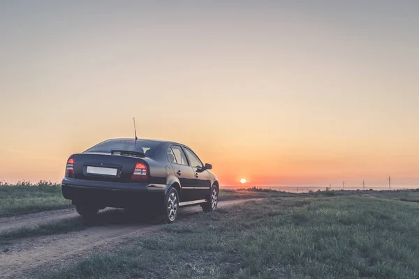 夕暮れの道で黒い車 — ストック写真