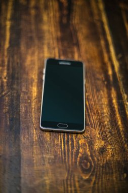 Ahşap masa üzerinde siyah cep telefonu.