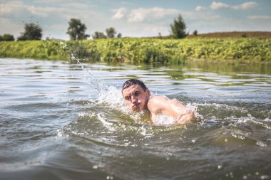 Genç adam nehirde yüzüyor..