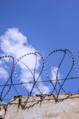 Gökyüzü arka plan üzerinde dikenli tel çit.