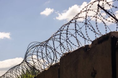 Gökyüzü arka plan üzerinde dikenli tel çit.