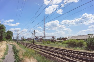 Tüylü bulutlar, tren ve bir eski harap tesisi içinde belgili tanımlık geçmiş boyunca yeşil çim ile mavi bir gökyüzü.