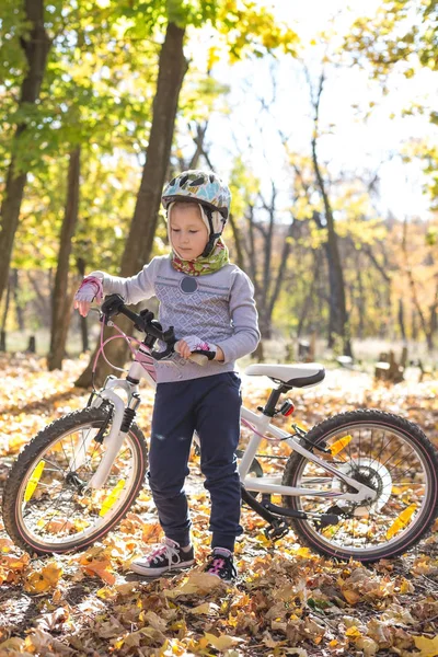 Sevimli küçük kız sonbahar ormandaki bir bisiklet ile.