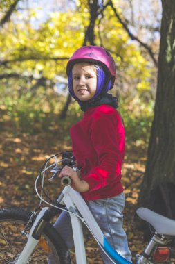 Sevimli küçük kız sonbahar ormandaki bir bisiklet ile.