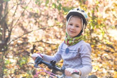 Küçük kızla sonbahar ormandaki Bisiklet kask içinde.
