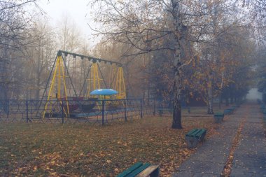 Lunaparktaki eski terk edilmiş bir sisli sonbahar sabahı banklar.