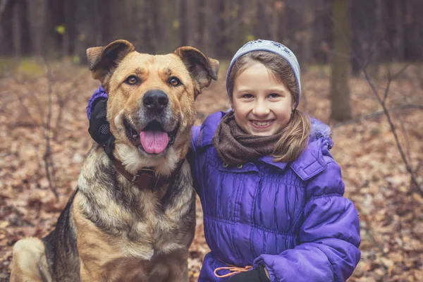 Portrait of a little girl and a big dog in the forest. Dog breed mastiff.
