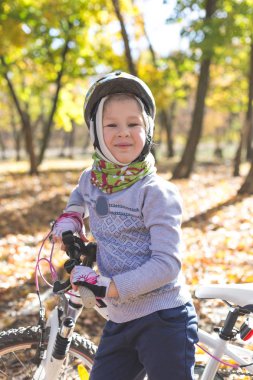 Sevimli küçük kız sonbahar ormandaki bir bisiklet ile.