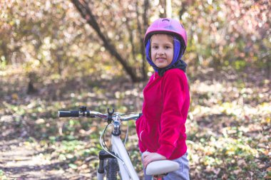 Sevimli küçük kız sonbahar ormandaki bir bisiklet ile.