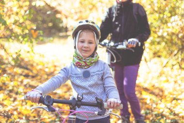 Küçük kızla sonbahar ormandaki Bisiklet kask içinde.