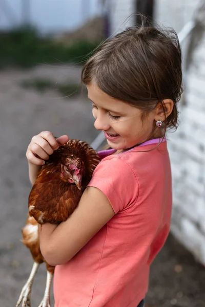 Little rural girl with chicken in her arms.