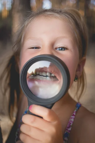 Mała Dziewczynka Położyć Szkło Powiększające Usta Pokazać Aparatów Ortodontycznych Krzywe — Zdjęcie stockowe