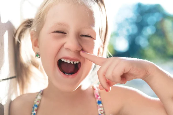 Dziewczynka wskazuje palcem na chwiejny ząb dziecka. — Zdjęcie stockowe
