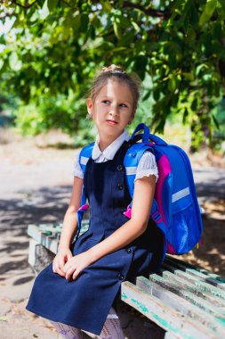 Bir bankta oturan bir ilkokul öğrencisi.