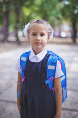 Parkta sırt çantası ile şirin küçük kız öğrenci.