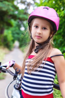 Bir bisiklet yakınındaki pembe bir kask içinde küçük şirin kız