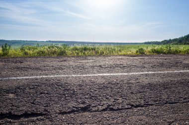Arka planda bir bölme şeridi, çim ve gökyüzü ile eski yol.
