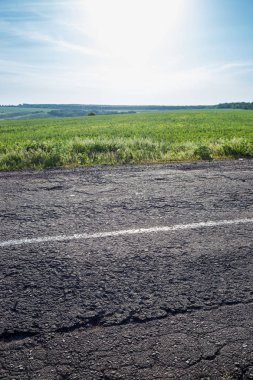 Arka planda bir bölme şeridi, çim ve gökyüzü ile eski yol.