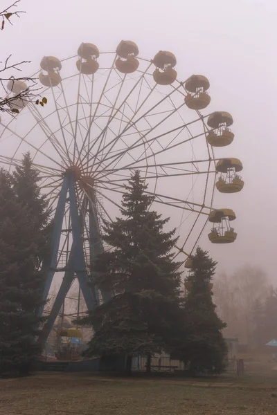 Rueda de la fortuna en un viejo parque abandonado en otoño en espesa niebla — Foto de Stock