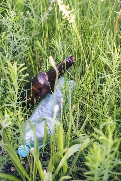 Glas-och plastflaska i gräset. — Stockfoto