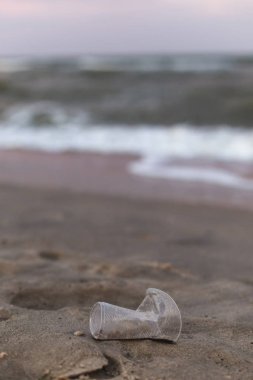 Deniz kıyısında küçük bir plastik bardak.